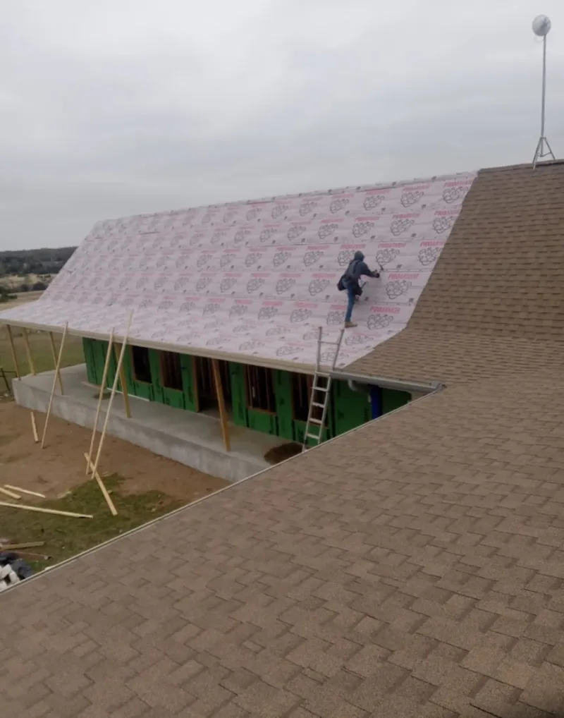 Worker preparing underlayment for a metal roof installation in Sparta